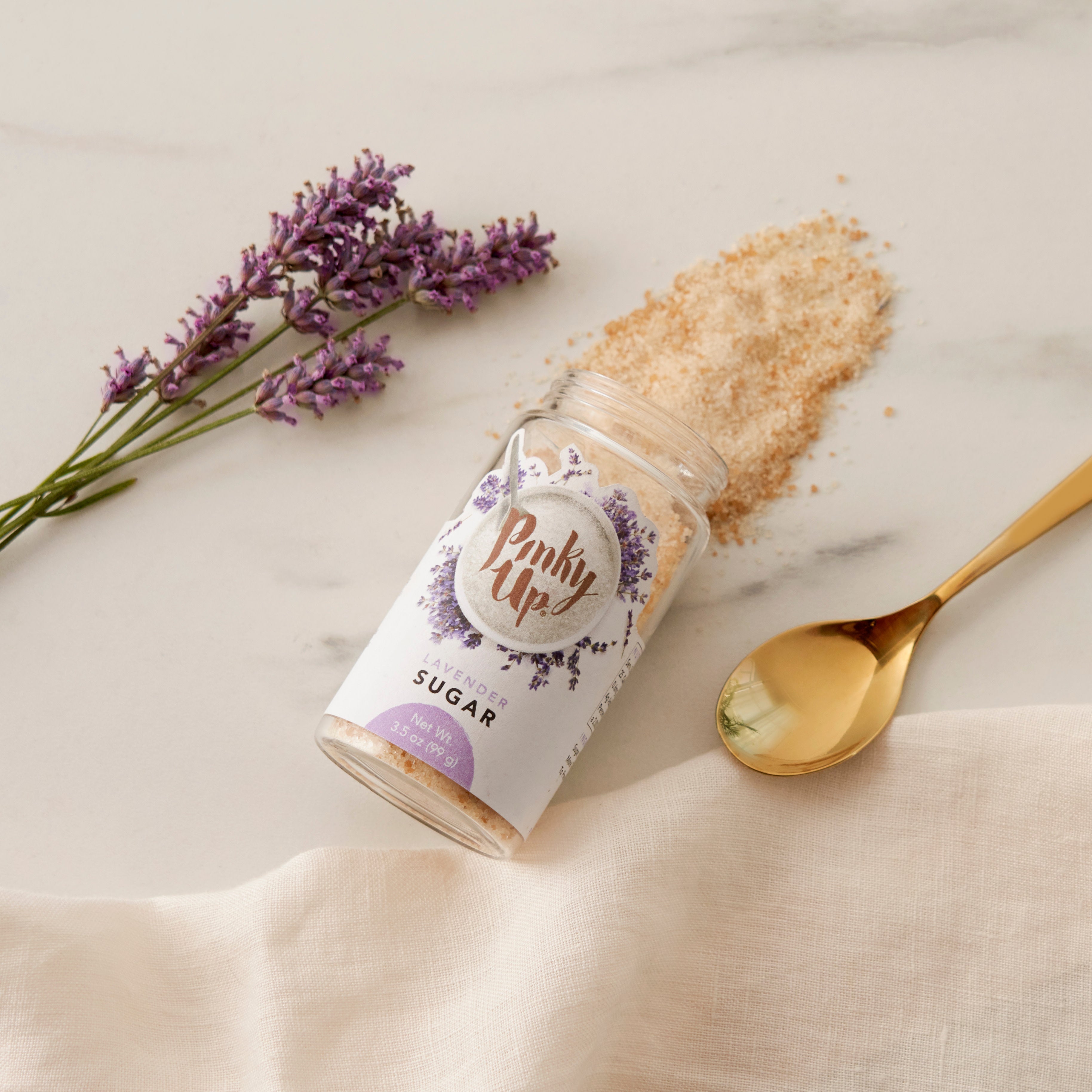 Pinky Up Lavender Sugar in a clear jar with a lavender hue, displayed on a neutral background