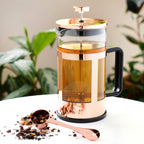 Pinky Up Piper Rose Gold Press Pot with a sleek design, featuring a rose gold finish and a glass body for brewing coffee.