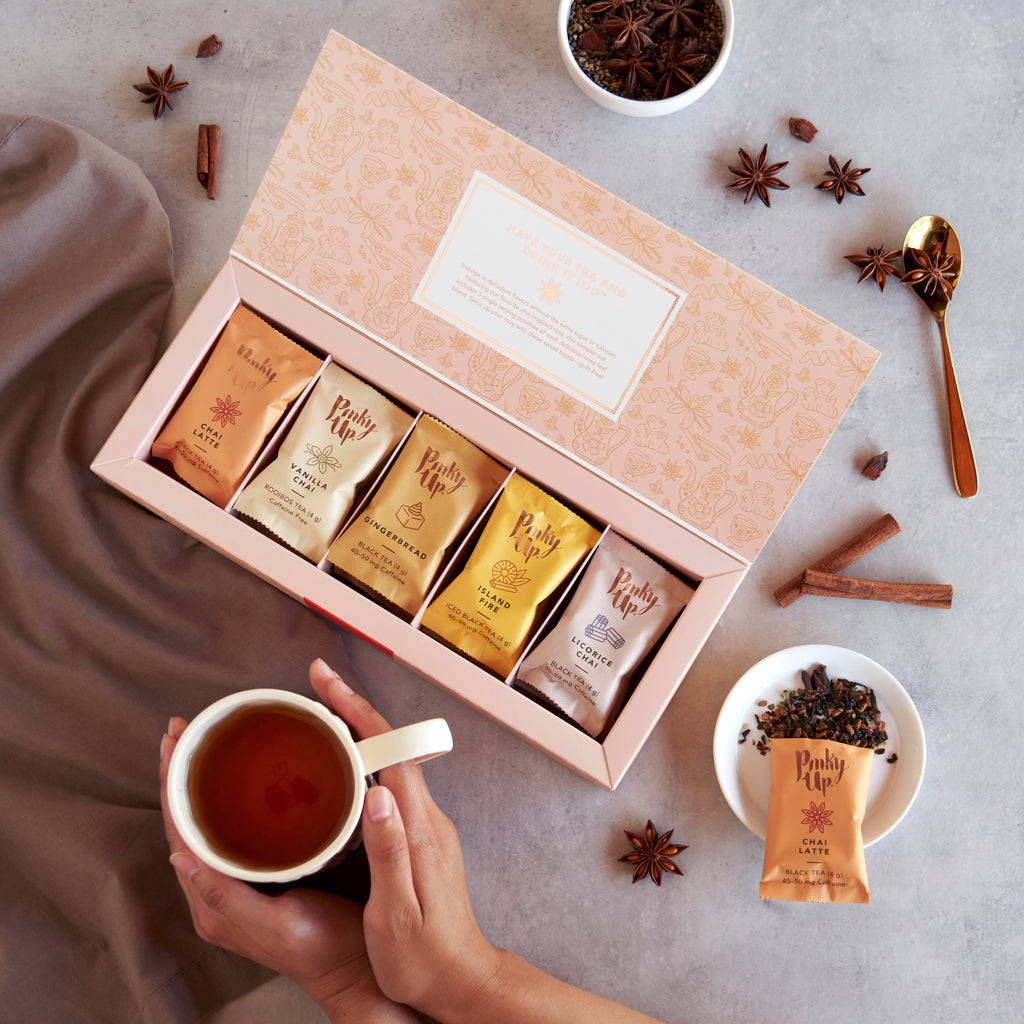 Pinky Up Chai Loose Leaf Tea Sampler featuring colorful tea packaging and assorted chai flavors displayed in a neat arrangement.