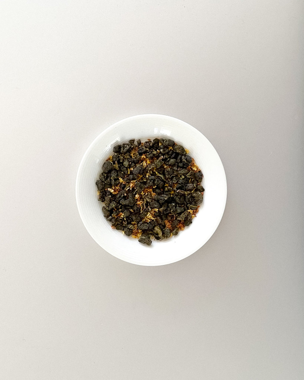 Teappo Osmanthus Oolong tea leaves displayed in a clear container, showcasing the delicate, fragrant tea.