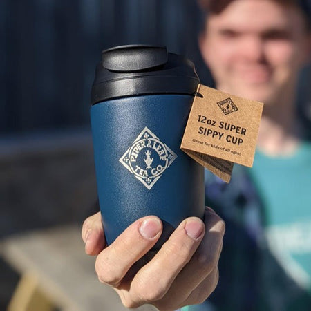 Piper and Leaf Super Sippy Travel Tumbler - Hot & Iced! in navy blue with logo, flexible straw, and flip-top lid for beverages.