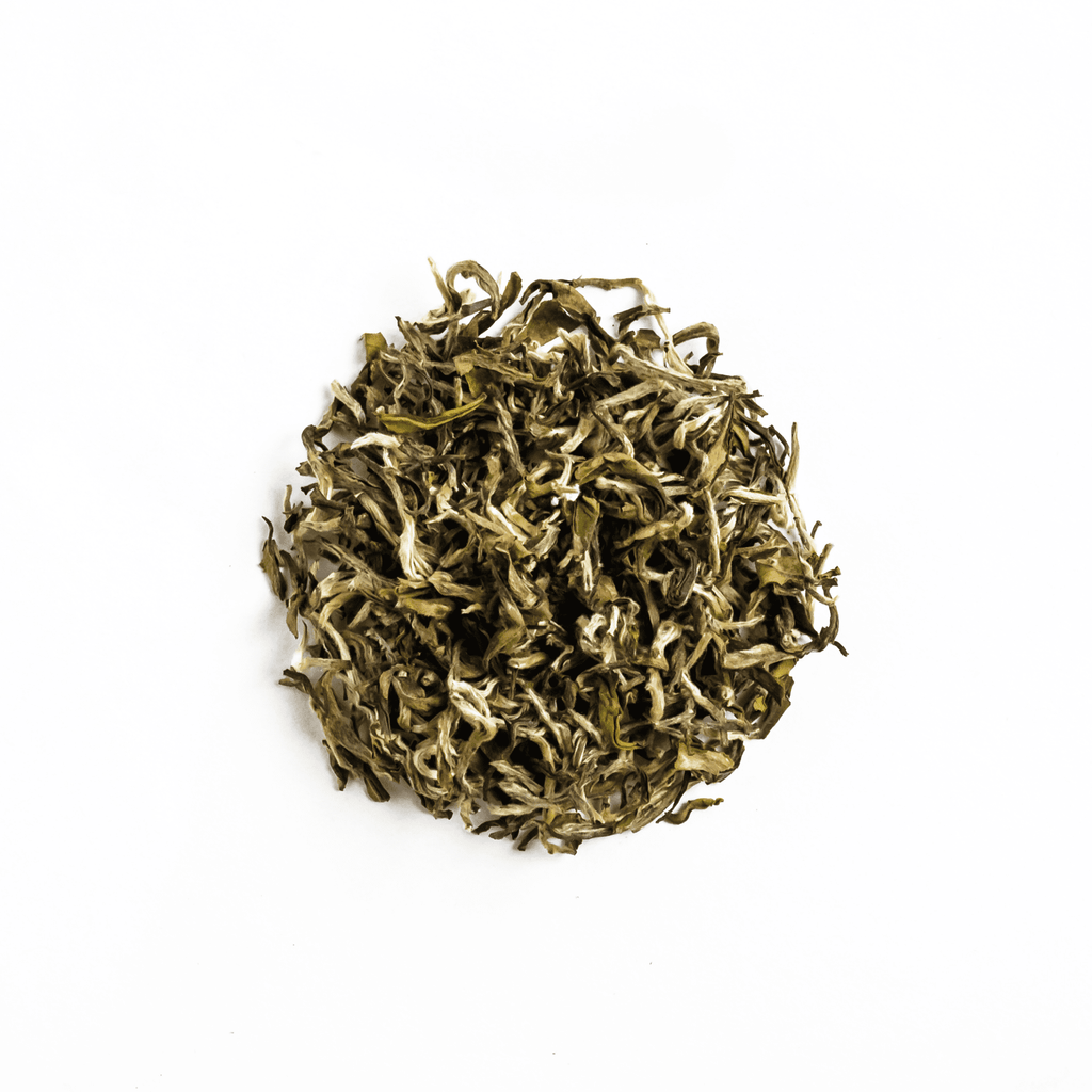 White Prakash tea from Nepal Tea in a loose leaf format, displayed in a clear packaging on a wooden surface.