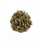 White Prakash tea from Nepal Tea in a loose leaf format, displayed in a clear packaging on a wooden surface.